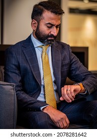 A Vertical Shot Of A Businessman In A Blue Suit And Yellow Tie Checking His Watch For The Time In Canada