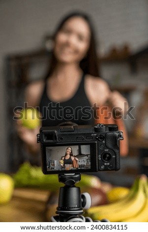 Vertical shot of camera screen showing woman holding fruits and vegetables for her video diary. Streaming on live for social media, vlogging and blogging online about dietary meal