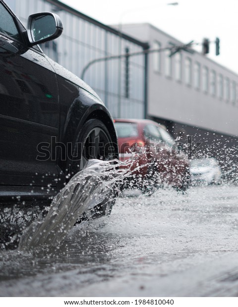 A\
vertical shot of a car splashing water on the\
street