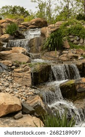 A vertical shot of a cascade flowing down the rocks covered with green grassf