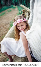 A Vertical Shot Of A Caucasian Blonde Girl With A Flower Hairband Under Sunlight