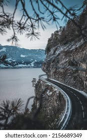 A Vertical Shot Of A Cliff Side Road By A Lake In Winter