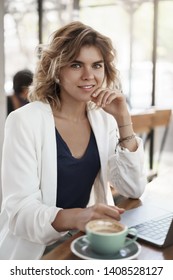 Vertical Shot Confident Successful Blond Curly-haired Young Female Entrepreneur Freelance Social Media Manager Work Outside Office Gig Economy Concept, Drink Coffee Cafe Sit Near Laptop