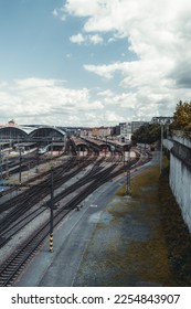 A vertical shot of a contemporary railroad terminal depot station with plenty of railway junctions and branches, outdoor and indoor platforms, trains, and locomotives on a cloudy day, Prague - Shutterstock ID 2254843907