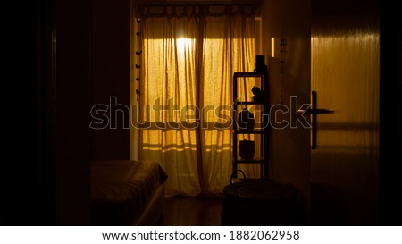 A vertical shot of a cozy room with a retro design and closed windows at the sunset time