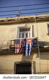 A Vertical Shot Of A Cuban And An American Flag Hanging On A Balcony