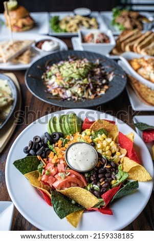 A vertical shot of delicious dinner table with salads and nachos