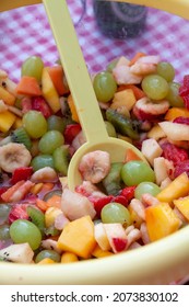 A Vertical Shot Of A Delicious Fruit Salad In A Clear Plastic Bowl With A Spoon In It