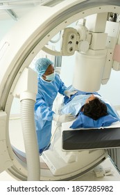 Vertical Shot Of A Doctor Preparing A Patient Lying Down On A Bed For An X-Ray In The Hospital