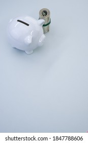 A vertical shot of dollar bills and a piggy bank on a blue surface - Shutterstock ID 1847788606