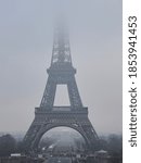 A vertical shot of the Eiffel Tower covered in mist