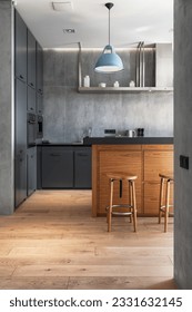 Vertical shot of elegant kitchen with gray cabinet, wooden table and chairs on parquet. Stylish interior design in modern apartment. Tidy, neat storage concept