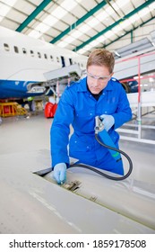 Vertical Shot Of An Engineer In Uniform Inspecting Airplane Parts At A Hangar.