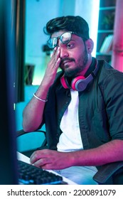 Vertical Shot Of Exhausted Or Tired Gamer Rubbing His Eyes While Playing Video Game During Late Night - Concept Of Gaming Addiction And Health Care.