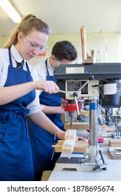 Vertical Shot Of A Female High School Student Using A Drill During A Woodworking Class.