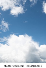 A vertical shot of a fluffy white cloud against a bright azure sky. The clean, unobstructed blue space creates a serene and fresh backdrop ideal for nature and travel designs.