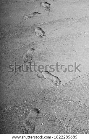 A vertical shot of footsteps on grey sand texture