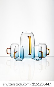 the Vertical shot of a glass blue transparent  cups and juice pot with a white background