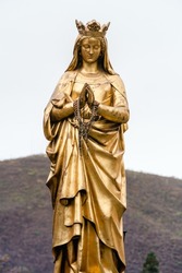 A Vertical Shot Of The Golden Statue Of Mary
