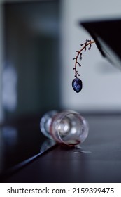 A Vertical Shot Of A Grape And A Spilled Wine On A Table