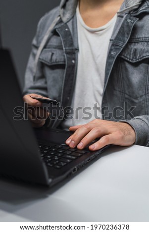 A vertical shot of a guy with his laptop and credit card making a payment online
