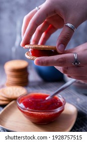 A Vertical Shot Of Hands Holding Fresh Maria Cookie (galletas Maria) With Strawberry Jam