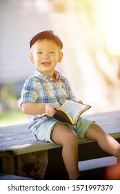 A Vertical Shot Of A Happy Child Holding The Bible While Smiling At The Camera