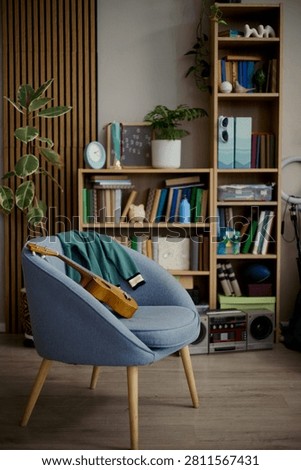 Vertical shot of home study corner displaying guitar on chair beside bookshelf, suggesting creative learning and teen lifestyle. Useful for education, music class, home tutoring ads