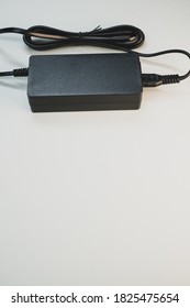 A Vertical Shot Of A Laptop Charger Isolated On A Gray Background