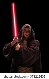 Vertical shot of a male warrior with red laser sword on black background
