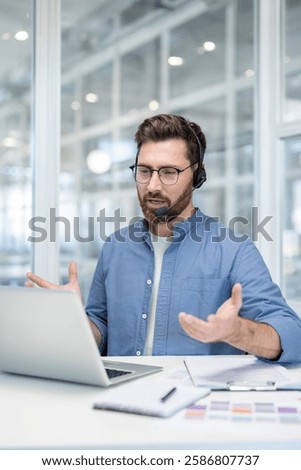 Vertical shot, man with headset talking and consulting customers remotely at workplace. Serious and focused employee helping customer remotely.