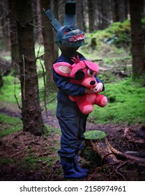 A Vertical Shot Of A Man Wearing A Scary Rabbit Costume And Holding A Pirate Rabbit In His Hand In The Middle Of The Forest