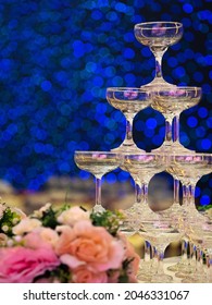 A Vertical Shot Of Martini Glasses Stacked Atop Of Each Other On A Blue Bokeh Background At A Wedding