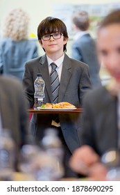 Vertical Shot Of A Middle School Student Walking With His Lunch In The School Cafeteria.