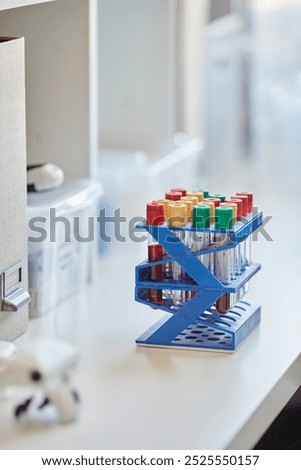 Vertical shot of multiple test tubes with blood or chemicals on plastic rack resting on scientists workstation in laboratory, copy space