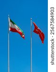 Vertical shot of national flags of Iran, Turkey swaying in wind on clear blue sky. Negotiations, diplomatic visits, meeting guests, friendship of peoples, trade between countries, signing of treaties.