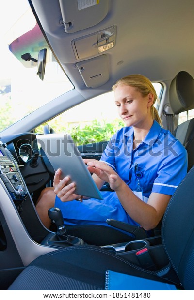 Vertical shot of a nurse using a digital tablet in\
her car