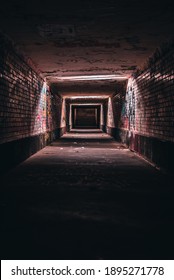 A Vertical Shot Of An Old Empty Underground Corridor Tunnel Of An Urban City With Graffiti Walls