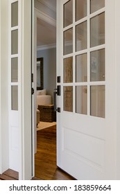 Vertical Shot Of An Open, Wooden Front Door From The Exterior Of An Upscale Home With Windows. 