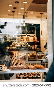 A Vertical Shot From Outside Of A Full Of Customers Bakery Shop With Tasty Desserts And Buns