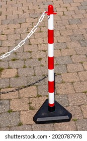 A Vertical Shot Of A Parking Bollard On The Cobblestone Sidewalk