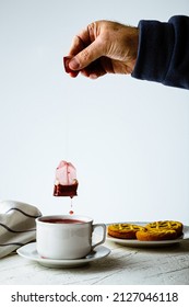 A Vertical Shot Of A Person Making Tea With A Teabag On The Table With Biscuits On It