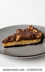 A Vertical Shot Of A Piece Of Caramel Cheesecake With Peanuts Isolated On A White Background