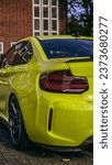 A vertical shot of the rear light of a yellow car parked on the driveway