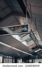 A vertical shot of a rectangular sign with Asian symbols in the airport