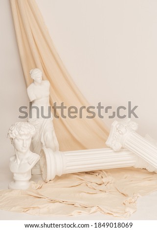 A vertical shot of the Renaissance epoch gypsum statues arranged with fabric on white background
