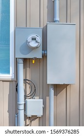 Vertical Shot Of A Residential Electric Meter Mounted On A Wall.