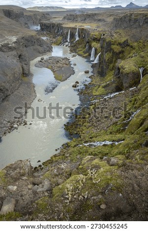 Vertical shot of river valley with multiple waterfalls streaming into it, Highlands, Iceland
