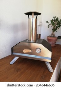 A Vertical Shot Of A Silver Pizza Oven On A Wooden Table In The Kitchen