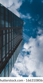 A vertical shot of a skyscraper under a sky full of clouds